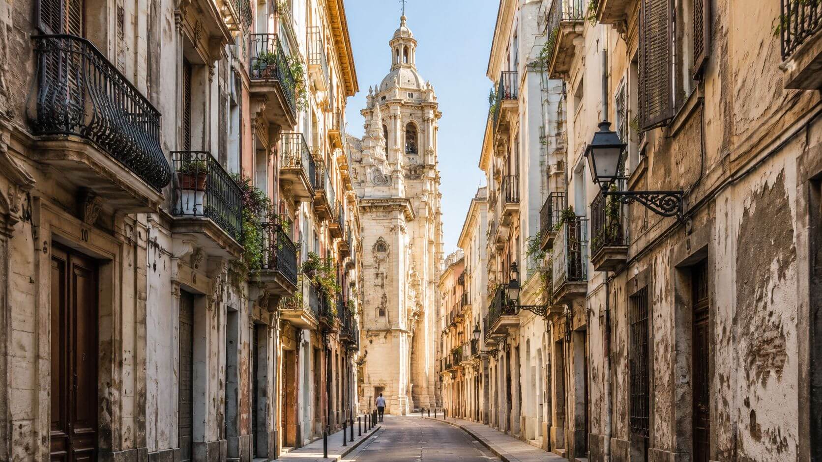 Certificados Energéticos | Rehabilitación edificios históricos Una calle estrecha y antigua en el centro histórico, con arquitectura clásica y una torre de iglesia.